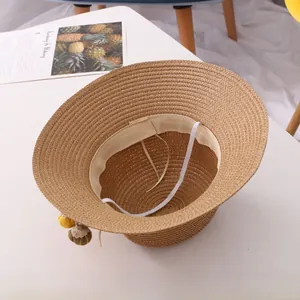 Detail view of woven straw sun hat with inner sweatband and decorative fuzzy pompoms