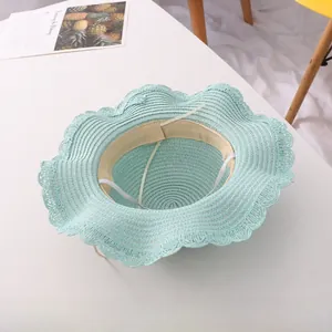 Detail view of mint green woven straw hat with wavy brim, sweatband, and elastic chin strap