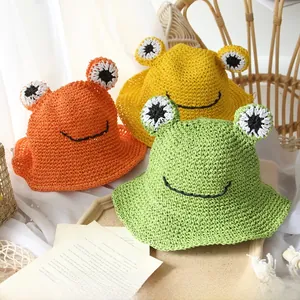 Detail of three handmade straw frog hats in orange, yellow and green colors for kids