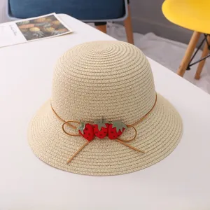 Détail d'un chapeau de paille beige pour fille avec fraises et nœud marron