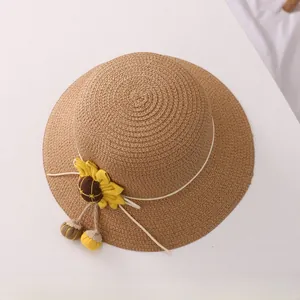 Detail of woven straw sun hat with yellow sunflower ornament and decorative tassels