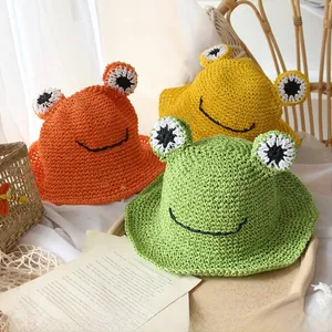 Detail of three handmade kids frog straw hats in orange, yellow and green colors