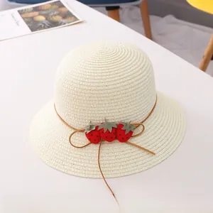 Détail d'un chapeau de paille pour fille avec de jolies fraises en tissu et un petit nœud