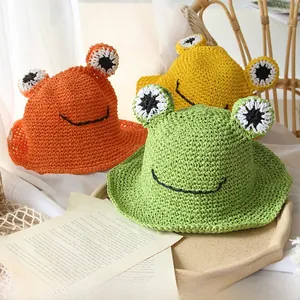 Detail of handmade straw hats with cartoon frog eyes and scalloped edges in various colors