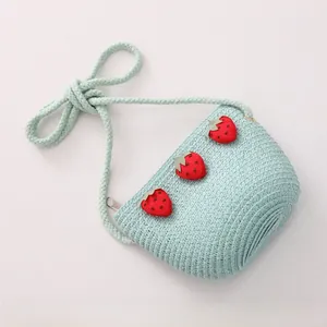 Détail d'un sac tressé vert menthe pour enfants avec fraises et bandoulière en coton
