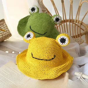 Detailed close-up of handmade crochet frog sun hats in vibrant green and yellow straw