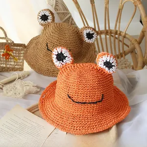 Detail of handwoven orange and khaki straw hats with cute frog eye decorations