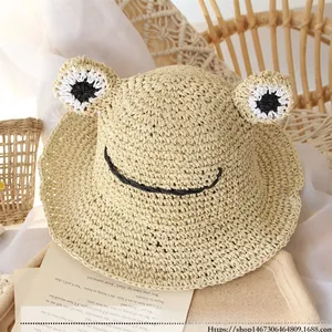 Detailed view of handmade straw hat with cute frog eyes and wave brim on a tray