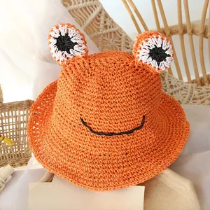 Detailed texture of hand-woven orange frog straw hat for kids featuring cute large 3D eyes