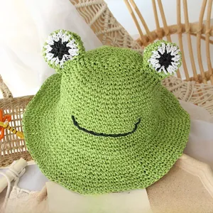 Close-up of green handmade straw hat with frog eyes and wave brim for kids sun protection