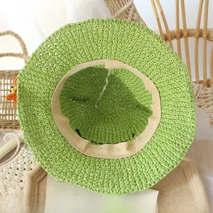 Detailed interior of a handmade green straw hat with adjustable strap and orange knit flower