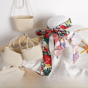 Detail of woven kids straw hat with floral ribbons and matching beige crochet mini bags