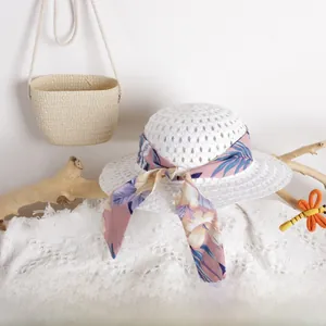 Close-up of white breathable hollow straw hat with floral ribbon and matching woven bag