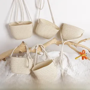 Detail of mini straw woven shoulder bags for kids with rustic fiber texture and cotton straps