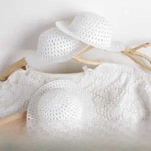 Detailed macro of three white hollow woven mini mesh hats for kids with floral patterns