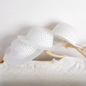 Detailed view of three white crochet hollow knit sun hats for kids on wooden decor