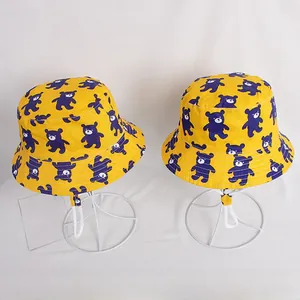 Detail of yellow kids bucket hats with purple bear patterns and adjustable chin straps
