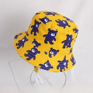 Detail of yellow kids bucket hat with blue bear prints and white chin strap cord