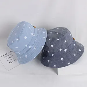 Blue baby bucket hats with white star patterns and wooden buttons on white stand