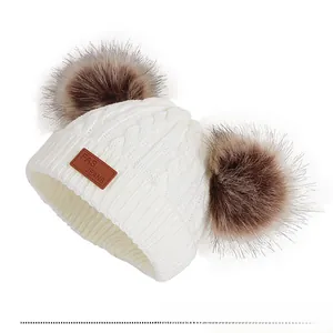 Détails du tricot torsadé blanc et des oreilles en fourrure de ce bonnet bébé