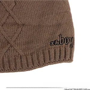 Detail of coffee brown knit beanie showing rhombus pattern texture and xhboy embroidery