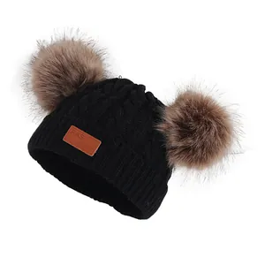 Bonnet en tricot noir pour enfant avec doubles pompons en fourrure et écusson en cuir