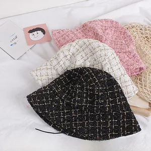 Detail of tweed bucket hats in pink, white, and black with shiny gold thread weaving