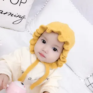 Bright yellow knitted baby winter hat with ruffle edges and ties for infants