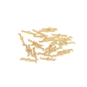 Dettaglio macro di connettori alfabetici placcati oro 18K con cristalli di zircone micro-incastonati