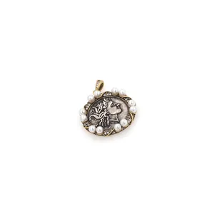 Macro view of vintage oval pendant with silver relief, pearls, and gold wavy border