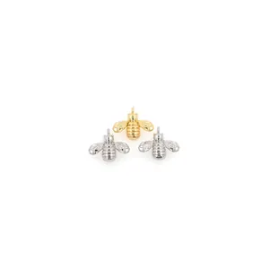 Macro detail of 18K gold and silver bee pendants with exquisite polished textures