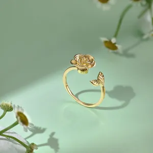 Nahaufnahme eines goldenen verstellbaren Rings mit Rose und Blatt auf floralem Hintergrund