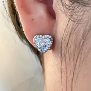 Détail d'une boucle d'oreille puce en forme de cœur avec halo de zircons sur l'oreille