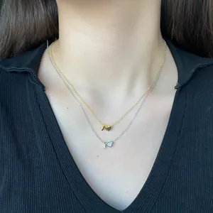 Detail of layered S925 silver heart necklaces with letter I pendant on black knitwear