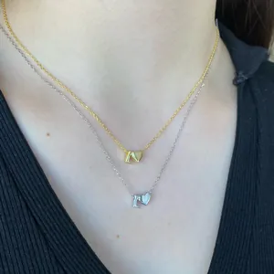 Layered gold and silver necklaces featuring 3D heart and letter L charms on a model