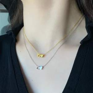 Close-up of gold and silver S925 sterling silver heart and letter O necklaces on model