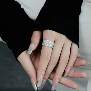 Gros plan d'une bague large en argent avec design tressé et zircons scintillants