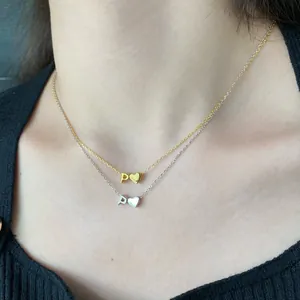 Detail of S925 silver gold and silver layered necklaces with P letter and heart pendants