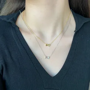 Close-up of gold and silver S925 heart necklaces with V-letter charm layered on model