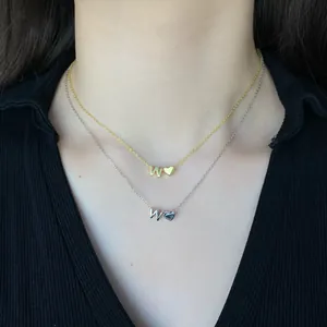 Detail of layered S925 silver necklaces with letter W and heart pendant on model