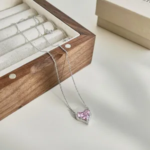 Macro view of heart-shaped pink gemstone pendant with silver s925 chain in a wooden box