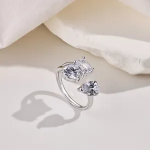 Detalle de anillo ajustable de plata con circonitas en forma de corazón, esmeralda y pera
