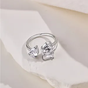 Anillo de plata S925 con circonitas en forma de pera y corazón sobre fondo de piedra