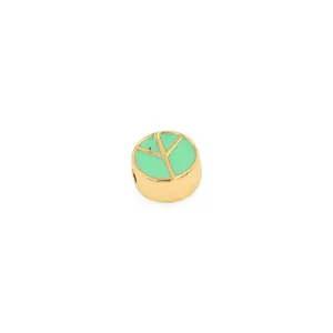 Dettaglio macro di una perla placcata oro 18K con segno della pace in smalto verde