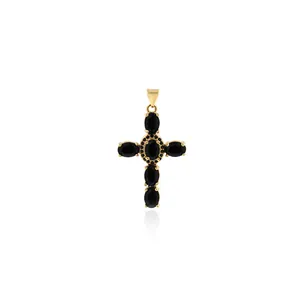 Detailed macro view of 18K gold-plated cross pendant with black oval stones and micro-pave