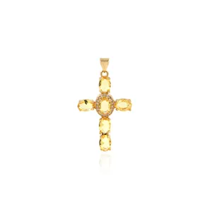 Macro detail of 18K gold plated cross pendant with yellow cubic zirconia and tiny diamonds