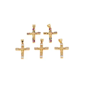 Detalle de colgantes de cruz bañados en oro de 18K con circonitas de colores y relieve de Jesús