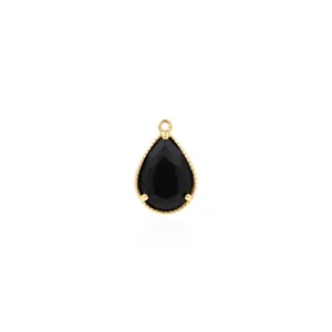 Vista macro de colgante de gota con gema negra y borde perlado chapado en oro 18K
