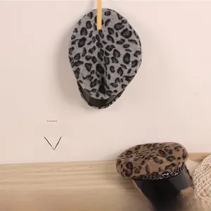 Détail d'un béret léopard avec chaîne métallique et visière noire brillante en relief