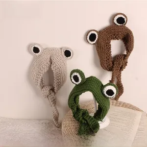 Close-up of chunky knit frog headbands in three colors with big eye detail for kids